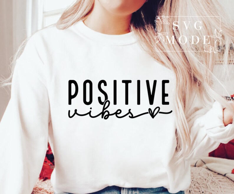 Peut inclure: Sweat-shirt blanc avec un texte noir qui dit "POSITIVE vibes" avec un petit symbole de c&oelig;ur.