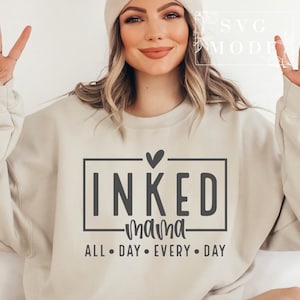 May include: A beige sweatshirt with the text "INKED mama ALL DAY EVERY DAY" in a black box with a small heart above the box.