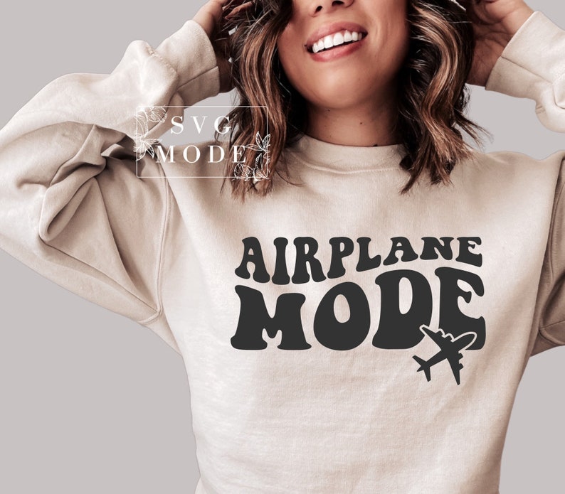 Puede incluir: Una sudadera beige con el texto "AIRPLANE MODE" en letras retro negras. Un peque&ntilde;o icono de avi&oacute;n est&aacute; a la derecha del texto.