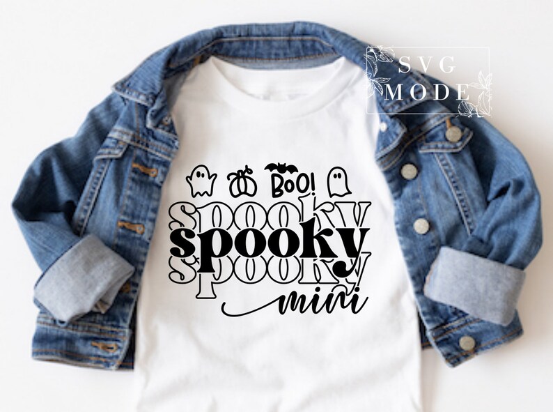 Puede incluir: Camiseta blanca con un dise&ntilde;o gr&aacute;fico negro que dice "spooky mini" con fantasmas, calabazas y murci&eacute;lagos alrededor del texto.