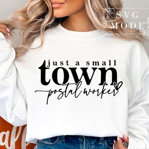 May include: White sweatshirt with black text that reads "Just a small town postal worker" with a small heart symbol.