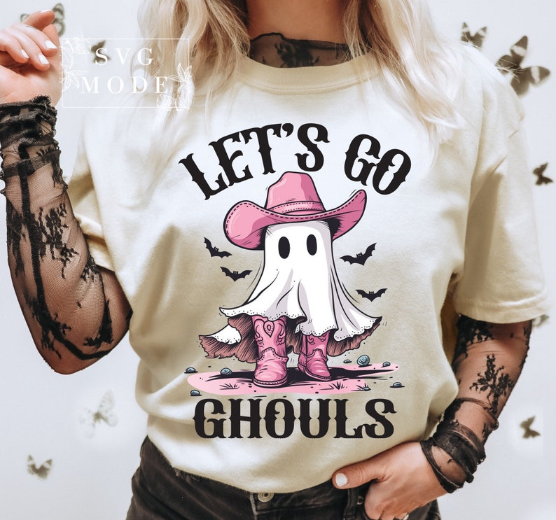 Może przedstawiać: Biała koszulka z nadrukiem ducha w r&oacute;żowym kowbojskim kapeluszu i butach. Na koszulce widnieje napis "Let's Go Ghouls".
