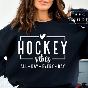 Puede incluir: Sudadera negra con texto blanco que dice "Hockey vibes all day every day" con un peque&ntilde;o coraz&oacute;n sobre la palabra "Hockey".