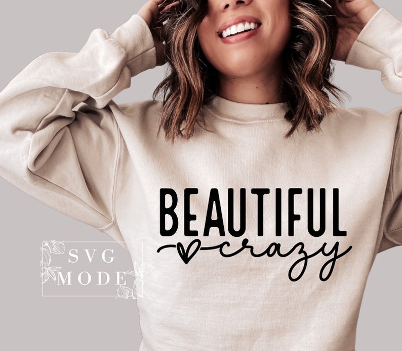 Pode incluir: Uma camisa de moletom bege com o texto "BEAUTIFUL crazy" em letras pretas. Um pequeno cora&ccedil;&atilde;o &eacute; desenhado entre as palavras.