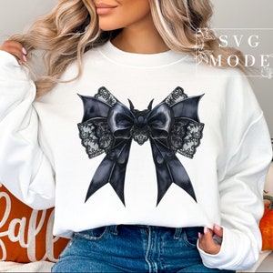 May include: A white sweatshirt with a black and white lace bow design. The bow is large and has a gothic style.