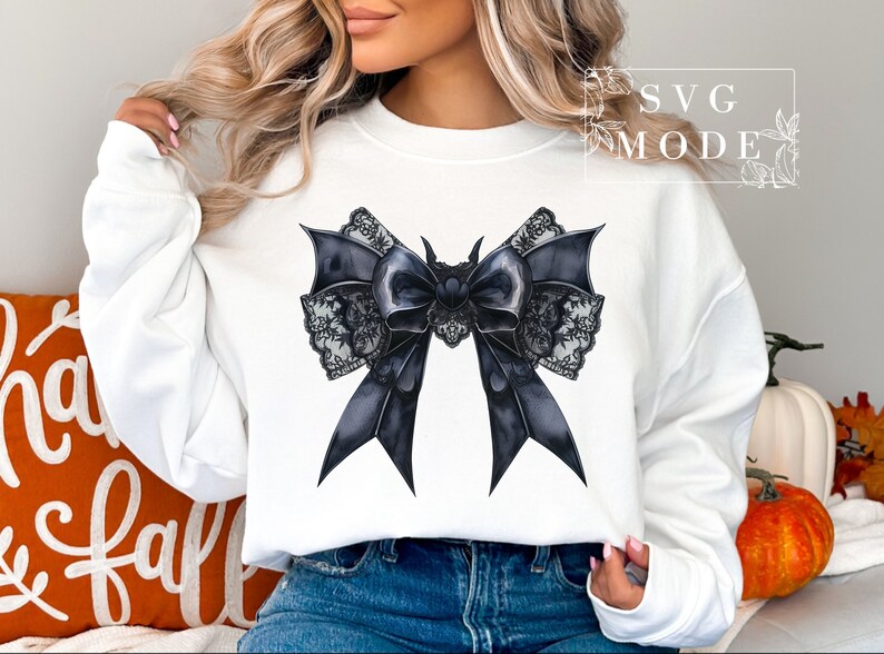 May include: A white sweatshirt with a black and white lace bow design. The bow is large and has a gothic style.
