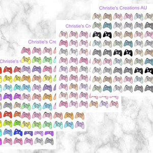 May include: A sheet of colorful game controller stickers with the text "Christie's Creations AU" at the top. The stickers are arranged in rows and columns, and each sticker features a different color and design.