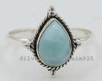 May include: A silver ring featuring a teardrop-shaped blue gemstone set in a delicate, ornate design.