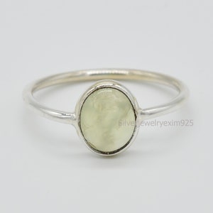 May include: A silver ring with a light green oval gemstone.