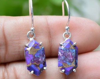 Puede incluir: Un par de pendientes de plata con colgantes de piedras preciosas de color púrpura y dorado. Las piedras preciosas son una mezcla de púrpura, dorado y blanco.
