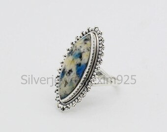 May include: A silver ring with a blue and white oval-shaped stone set in a decorative silver bezel. The ring has a beaded edge.