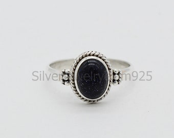 Puede incluir: Un anillo de plata con una piedra ovalada de color azul oscuro engastada en un engaste de plata. El engaste tiene un diseño de cuerda y pequeñas cuentas de plata a cada lado.