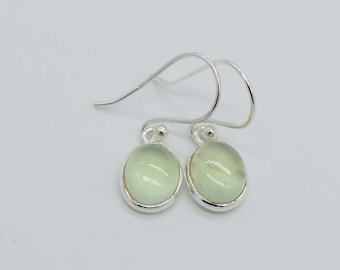 May include: A pair of silver dangle earrings with oval-shaped green gemstones.