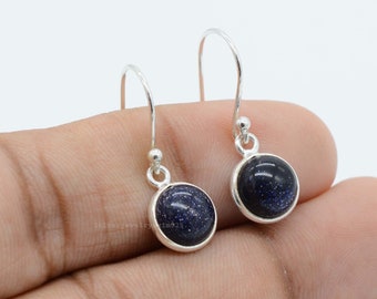 May include: A pair of silver dangle earrings with blue sunstone gemstones. The earrings have a simple design with a round gemstone and a hook closure.