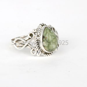 May include: A silver ring with a green and brown teardrop-shaped stone set in a detailed silver setting.