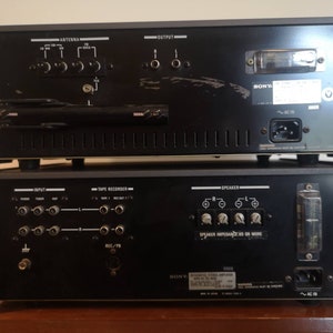 Puede incluir: Vista trasera de un receptor est&eacute;reo y un amplificador Sony vintage. El receptor tiene una cara de metal negro con una perilla plateada y una antena de pl&aacute;stico negro. El amplificador tiene una cara de metal negro con perillas plateadas y un cable de alimentaci&oacute;n de pl&aacute;stico negro.