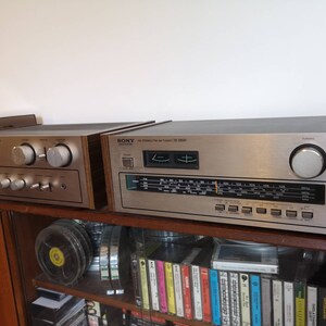 Puede incluir: Dos receptores est&eacute;reo vintage de Sony con paneles de madera. El receptor superior es un Sony ST-5050 plateado y negro con un dial de sintonizaci&oacute;n y una perilla plateada. El receptor inferior es un Sony plateado con dos perillas plateadas grandes.