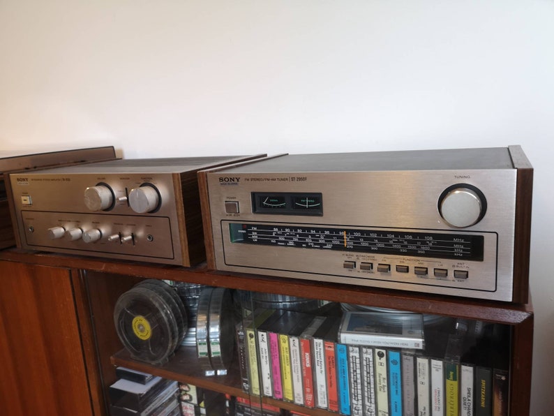 Puede incluir: Dos receptores est&eacute;reo vintage de Sony con paneles de madera. El receptor superior es un Sony ST-5050 plateado y negro con un dial de sintonizaci&oacute;n y una perilla plateada. El receptor inferior es un Sony plateado con dos perillas plateadas grandes.