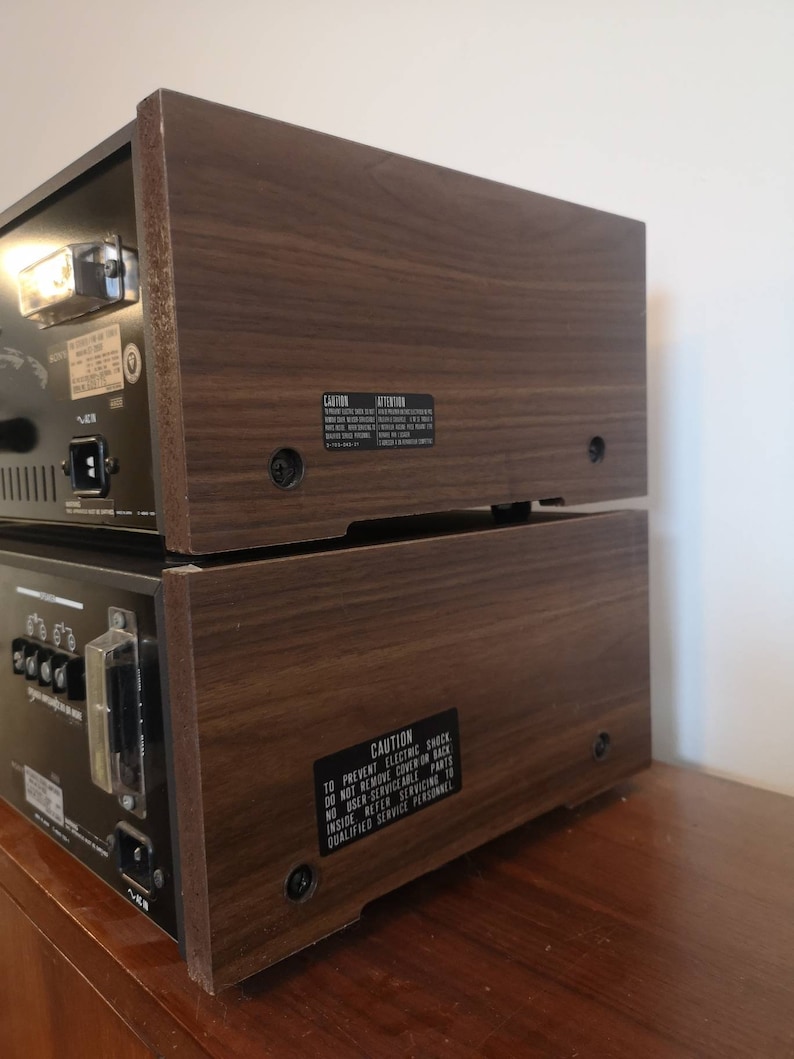 Puede incluir: Un sistema est&eacute;reo vintage con un gabinete de madera. La parte posterior del sistema tiene una etiqueta de precauci&oacute;n que dice "Para evitar descargas el&eacute;ctricas, no retire la cubierta o la parte posterior. No hay piezas reparables por el usuario en el interior. Consulte el servicio t&eacute;cnico a personal de servicio cualificado."