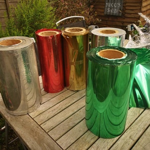 May include: Rolls of metallic wrapping paper in silver, red, gold, green, and a sheet of green wrapping paper.