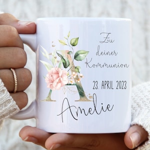 Könnte beinhalten: Weiße Keramiktasse mit Blumenmuster und dem Text "Zu deiner Kommunion 23. APRIL 2023 Amelie".
