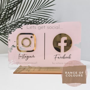 May include: A pink acrylic sign with gold Instagram and Facebook logos. The sign says "Lets get social..." with the Instagram handle "@byvictoriamaxwell" and "Facebook by victoria maxwell".
