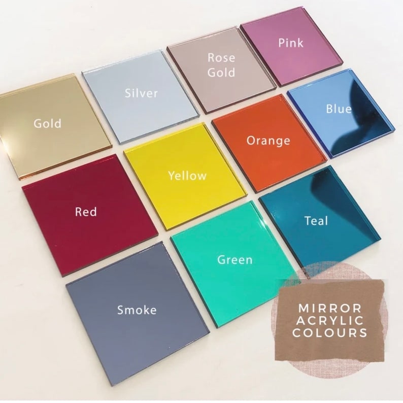 Op de afbeelding: Een verzameling van 12 vierkante acrylspiegeltegels in verschillende kleuren, waaronder goud, zilver, ros&eacute; goud, roze, oranje, geel, groen, teal, blauw, rood en rook. De tegels zijn gerangschikt in een raster en gelabeld met hun overeenkomstige kleuren. De tekst "MIRROR ACRYLIC COLOURS" staat op een bruin papieren label.