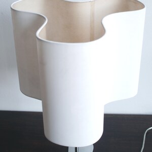 May include: A white table lamp with a unique, wavy, three-dimensional shade and a chrome base.