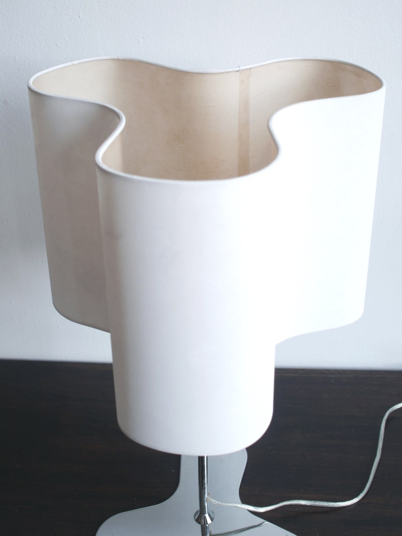 May include: A white table lamp with a unique, wavy, three-dimensional shade and a chrome base.