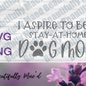 May include: A white wood sign with the text "I aspire to be a stay-at-home dog mom" in gray lettering. The sign also includes a paw print graphic. The sign is on a purple background with lavender flowers.