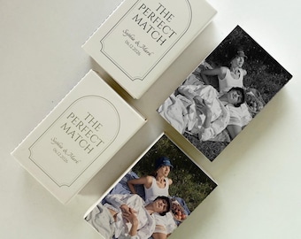 May include: Off-white matchboxes with the text "THE PERFECT MATCH" and names and a date. Two boxes feature black and white photos of people. The boxes are arranged on a white surface.