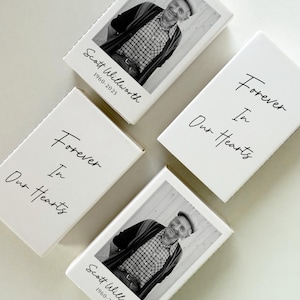 May include: Four white rectangular boxes with black text and a black and white photo. Two boxes read "Forever In Our Hearts." The other two boxes have a photo of a man and the text "Scott Willworth 1960-2025."