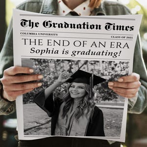 May include: A newspaper titled "The Graduation Times" with the headline "THE END OF AN ERA Sophia is graduating!" A black and white photo of a graduate in a cap and gown is featured. The newspaper is held by a person.