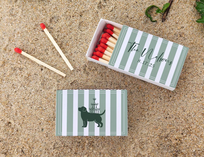 May include: Matchboxes with a green and white striped design. One box is open, revealing red-tipped matches. The top box has the text "The Nelsons" and the date "8.17.25". The bottom box features a dog silhouette with a champagne tower.