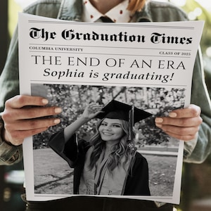 May include: A newspaper titled "The Graduation Times" with the headline "THE END OF AN ERA Sophia is graduating!" A black and white photo of a graduate in a cap and gown is featured. The newspaper is held by a person.
