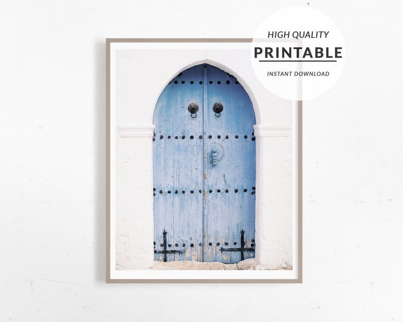 May include: A weathered blue wooden door with a decorative archway and metal accents. The door is set against a white wall.