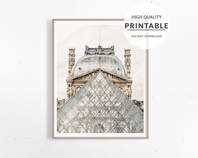May include: Framed print of the Louvre Museum in Paris, featuring the glass pyramid and the ornate architecture of the building. The print is labeled "HIGH QUALITY PRINTABLE INSTANT DOWNLOAD". The image is in neutral tones.
