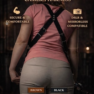 May include: A black dual camera harness crafted from full-grain leather. The harness is designed for security and comfort, compatible with DSLR and mirrorless cameras. The image also shows the text "Brown" and "Black".