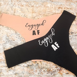 May include: Two pairs of underwear, one black and one peach, with the text "Engaged AF" printed on them.