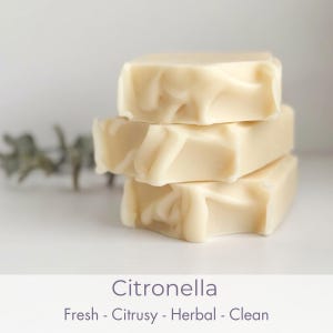 May include: Three stacked bars of light-colored soap with a creamy, marbled appearance. The soap is labeled "Citronella" with the words "Fresh - Citrusy - Herbal - Clean" below.