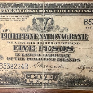 May include: A vintage five peso Philippine National Bank bill with a portrait of a man in a suit and tie. The bill is dated 1921 and has the text "Five Pesos" printed on it.