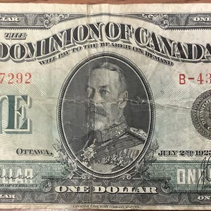 Może przedstawiać: Stary banknot jednodolarowy z Dominionu Kanady, przedstawiający portret króla Jerzego V i tekst "The Dominion of Canada Will Pay to the Bearer on Demand" w zielonym i czarnym atramencie.