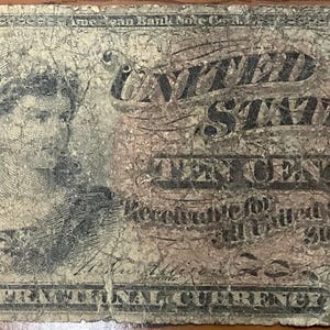 May include: Antique United States ten-cent fractional currency note. The note features a portrait of a woman on the left and the words "United States Ten Cents" in the center. The note is aged and shows signs of wear.