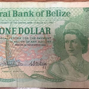 May include: A one-dollar banknote from the Central Bank of Belize. The bill features a portrait of a woman and the text "ONE DOLLAR". The bill has green and tan tones.