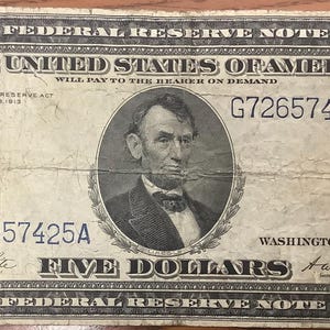 Peut inclure: Un billet de banque américain vintage de cinq dollars de 1914, présentant un portrait d'Abraham Lincoln au centre. Le billet porte le texte THE UNITED STATES OF AMERICA, FIVE DOLLARS, ainsi que le numéro de série G72657425A imprimé en noir.