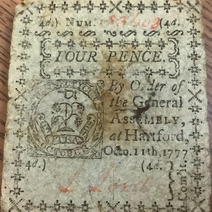 May include: Antique Four Pence note from the General Assembly at Hartford, dated October 11th, 1777. The note features ornate borders and text, including the denomination and the issuing authority.