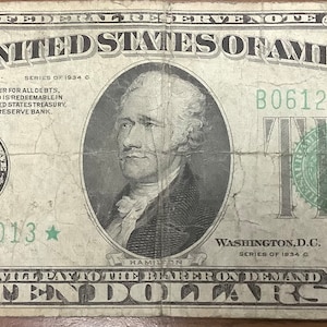 May include: A vintage ten dollar bill featuring a portrait of Andrew Jackson, the seventh president of the United States. The bill is in good condition with some wear and tear. The serial number is B06123013.