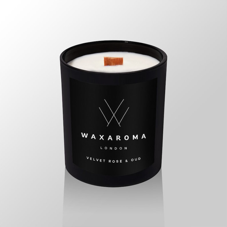 May include: Black candle jar with a white wax top and a wooden wick. The jar has a black label with the text "WAXAROMA LONDON VELVET ROSE & OUD".