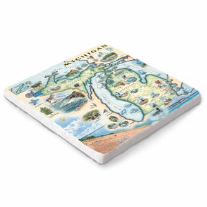 Puede incluir: Azulejo de cerámica cuadrado con un mapa detallado de Michigan con ilustraciones de lugares emblemáticos y fauna. El azulejo tiene un borde blanco y la palabra "MICHIGAN" está impresa en la parte superior. El mapa incluye los Grandes Lagos y varios puntos de interés.
