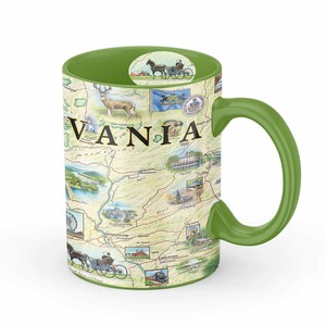 Puede incluir: Una taza de cerámica verde con asa. La taza presenta un mapa de Pensilvania con ilustraciones de puntos de referencia e interés. La palabra "PENNSYLVANIA" está impresa en letras grandes en la taza.
